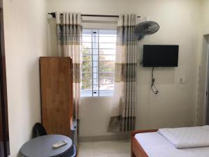 a room with a bed and a window with a television at Homestay 05 in Vung Tau