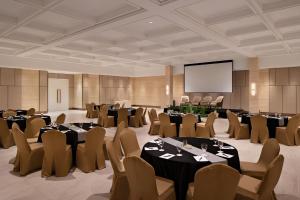 a conference room with tables and chairs and a screen at The Grand Mansion Menteng by The Crest Collection in Jakarta