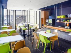 a restaurant with white tables and green chairs at ibis budget Gare de Poitiers in Poitiers