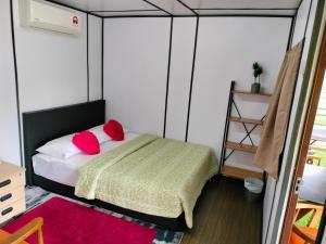 małą sypialnię z łóżkiem z czerwonymi poduszkami w obiekcie Inap Dusun Fraser Valley Kuala Kubu Bharu w mieście Kuala Kubu Bharu