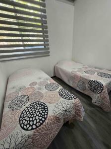 two twin beds in a room with a window at Departamento Amueblado con Alberca Pedregal C in Tamasopo