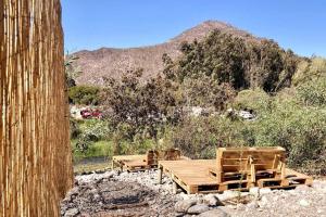 twee houten stoelen en een tafel in een veld bij Borde rio, Eco-Cabaña Jararankhu in Vicuña