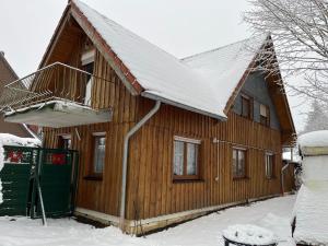 ein Holzhaus mit einem schneebedeckten Dach in der Unterkunft Holiday home Hexenstieg in the Harz Mountains in Elend