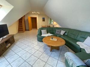 ein Wohnzimmer mit einem grünen Sofa und einem Tisch in der Unterkunft Holiday home Hexenstieg in the Harz Mountains in Elend
