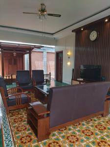 a living room with a couch and chairs and a clock at Guesthouse Syariah Griya Truntum in Lawean