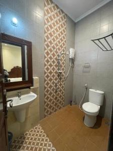 a bathroom with a toilet and a sink and a mirror at Guesthouse Syariah Griya Truntum in Lawean