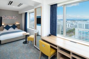 ein Hotelzimmer mit einem Bett, einem Schreibtisch und einem Fenster in der Unterkunft ART HOTEL Miyazaki Sky Tower in Miyazaki