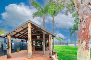 a building with palm trees in front of it at Kalbarri Tudor Holiday Park in Kalbarri