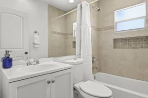 a white bathroom with a toilet and a sink at Palm Wave Says - Designers Stay - No Extra Fees in West Palm Beach +19 photos