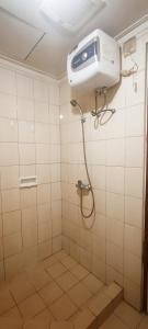 a shower in a white tiled bathroom at Convenient Apartments at West Jakarta in Jakarta