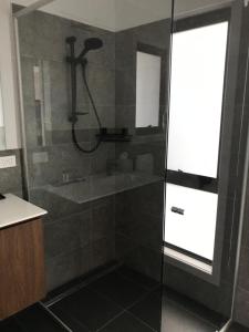 uma casa de banho com um chuveiro e uma porta de vidro em Derwent Mist Villas (Acacia Villa) 