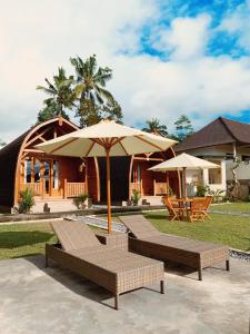 um grupo de cadeiras e um guarda-sol em frente a uma casa em Besakih Homestay & Villa em Besakih