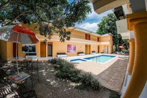 San Luis的住宿－Hostal Chez Holman，一个带遮阳伞和椅子的游泳池以及一座房子