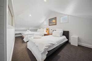 three beds in a room with white sheets at Tukidale Cottage - 3BR Cottage l WiFi l Air-Con l Relaxing Location in Crackenback