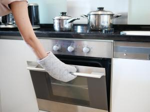 a woman is putting a box in an oven at Marriott Executive Apartments - Sukhumvit Park, Bangkok in Bangkok