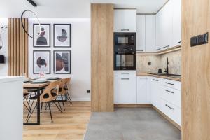 eine Küche mit weißen Schränken und einem Tisch mit Stühlen in der Unterkunft Apartamenty Polanowscy Baltic Marina Residence z mini SPA przy Bałtyckiej in Kołobrzeg