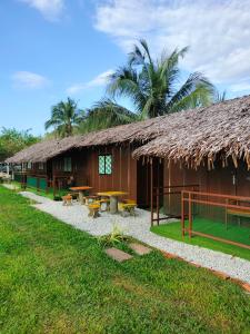 a building with a grass roof and picnic tables outside at Inap Dusun Fraser Valley Kuala Kubu Bharu in Kuala Kubu Baharu