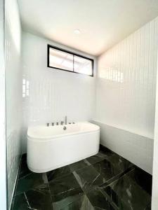 a white bathroom with a tub and a sink at Villa 173 - Two bedroom private villa in Ban Pak Chong Noi