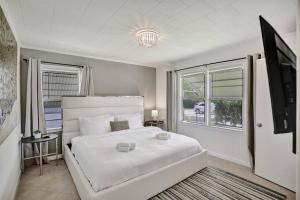 Un dormitorio blanco con una cama y un televisor. en Palm Wave Says - 5 Star - Quiet Area - Stocked, en West Palm Beach