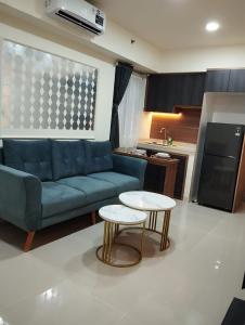een woonkamer met een blauwe bank en een tafel bij Classy and Elegance Apartment at Meikarta Tower Silverlake 