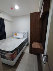 een kleine slaapkamer met een bed en een houten deur bij Classy and Elegance Apartment at Meikarta Tower Silverlake 