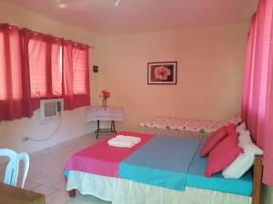 a bedroom with a bed with pink and blue sheets at Aglicay Beach Resort in Romblon