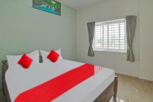 um quarto com uma cama com almofadas vermelhas e uma janela em Flagship M & M Hospitality em Devanhalli