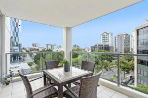 a balcony with a table and chairs and a view of the city at Cozy Unit in the heart of Brisbane in Brisbane