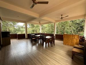 un porche cubierto con mesas, sillas y ventanas en Coorg Jungle Mist en Madikeri