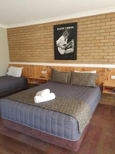 una camera con 2 letti e un letto a baldacchino sul muro di Winchester Motel a Moree