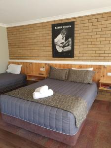 a bedroom with two beds and a poster on the wall at Winchester Motel in Moree