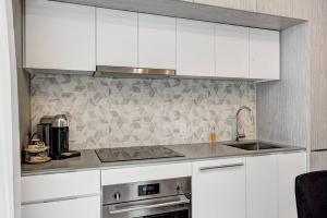 Una cocina con gabinetes blancos y un fregadero. en Luxury Downtown Escape Pool & Free Parking, en Montreal