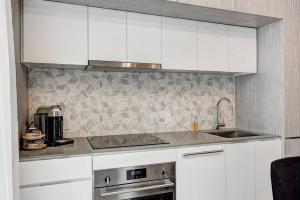 a kitchen with white cabinets and a sink at Beautiful Downtown condo with Pool and Parking in Montreal