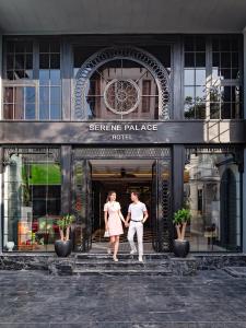 mężczyzna i kobieta wychodzący z hotelu w pałacu naukowym w obiekcie Hue Serene Palace Hotel w mieście Hue