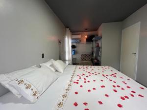 um quarto com uma cama branca com corações vermelhos em Loft Praia Brava - Itajaí Camboriú piscina e playground em Itajaí