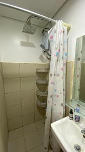 y baño con cortina de ducha y lavamanos. en Fully-furnished studio-type SMDC, en Dasmariñas