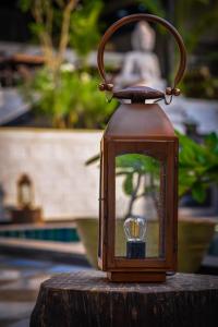 una lanterna seduta sopra un ceppo di legno di Anamiva, Goa - AM Hotel Kollection ad Anjuna