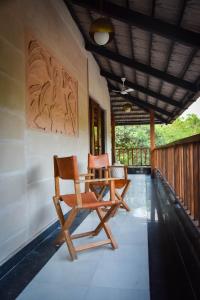 two wooden chairs sitting on the porch of a house at Anamiva, Goa - AM Hotel Kollection in Anjuna