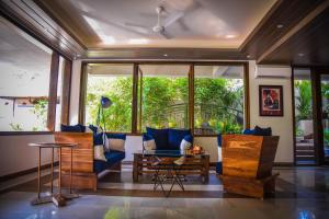 a living room with blue furniture and a large window at Anamiva, Goa - AM Hotel Kollection in Anjuna