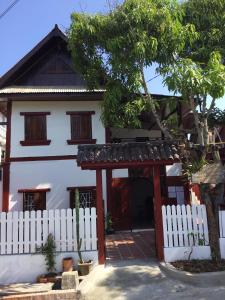 una casa blanca con una valla blanca y un árbol en Duang Champa 2 Guest house, en Luang Prabang