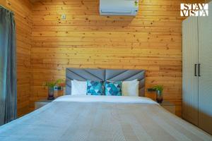 1 dormitorio con 1 cama en una pared de madera en StayVista at Secret Solace en Dehradun