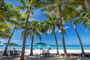 un groupe de palmiers sur une plage avec des chaises et des parasols dans l'établissement Villa White Pool, à Kamala Beach
