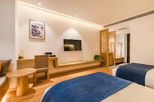 a hotel room with two beds and a desk at Supu Hotel - Zhengzhou CBD International Convention and Exhibition Center in Zhengzhou