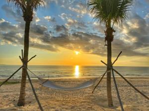 a hammock between two palm trees on a beach at Seaview Hotel - Arena Cam Ranh Resort in Cam Ranh