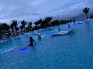 a woman in a pool with dolphins in the water at Seaview Hotel - Arena Cam Ranh Resort in Cam Ranh