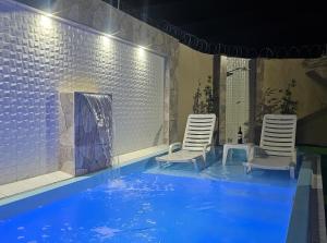 two chairs and a swimming pool with a fireplace at Marques Beach House in Marechal Deodoro