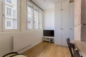 een woonkamer met een televisie en een tafel en stoelen bij L'Onyx - Beau studio atypique coeur Presqu'île in Lyon