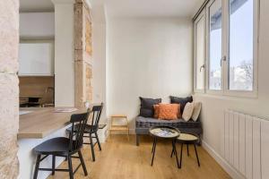 een woonkamer met een bank en een tafel en stoelen bij L'Onyx - Beau studio atypique coeur Presqu'île in Lyon