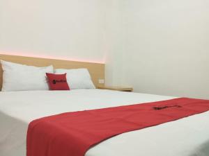 1 dormitorio con cama blanca con sábanas y almohadas rojas en RedDoorz Syariah @ Gedong Air Lampung en Kedaton