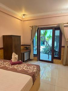 a bedroom with a bed and a large window at James Bungalow in Gili Trawangan